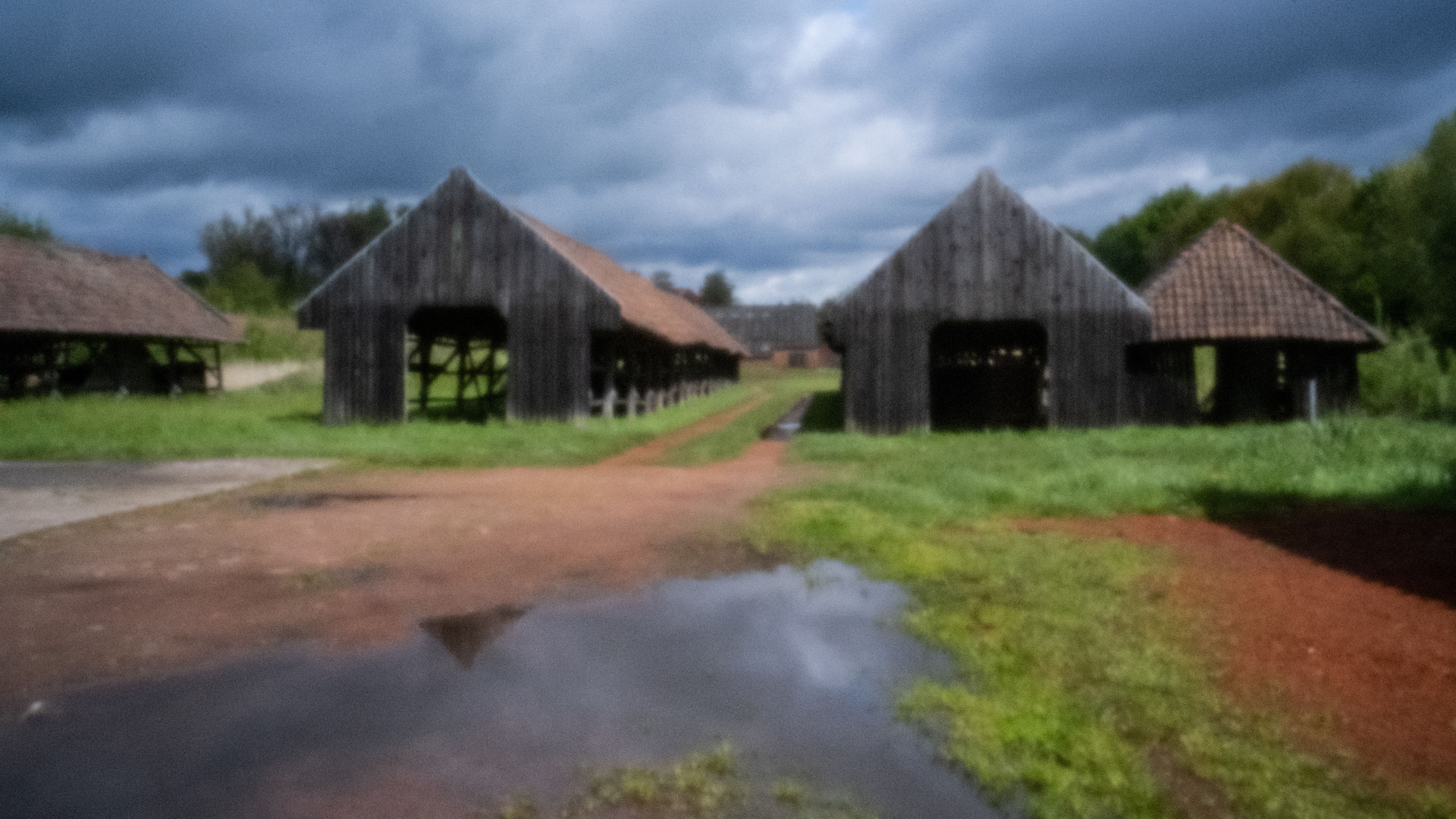 Houten droogloodsen van de steenbakkerij onder een donkere wolkenlucht