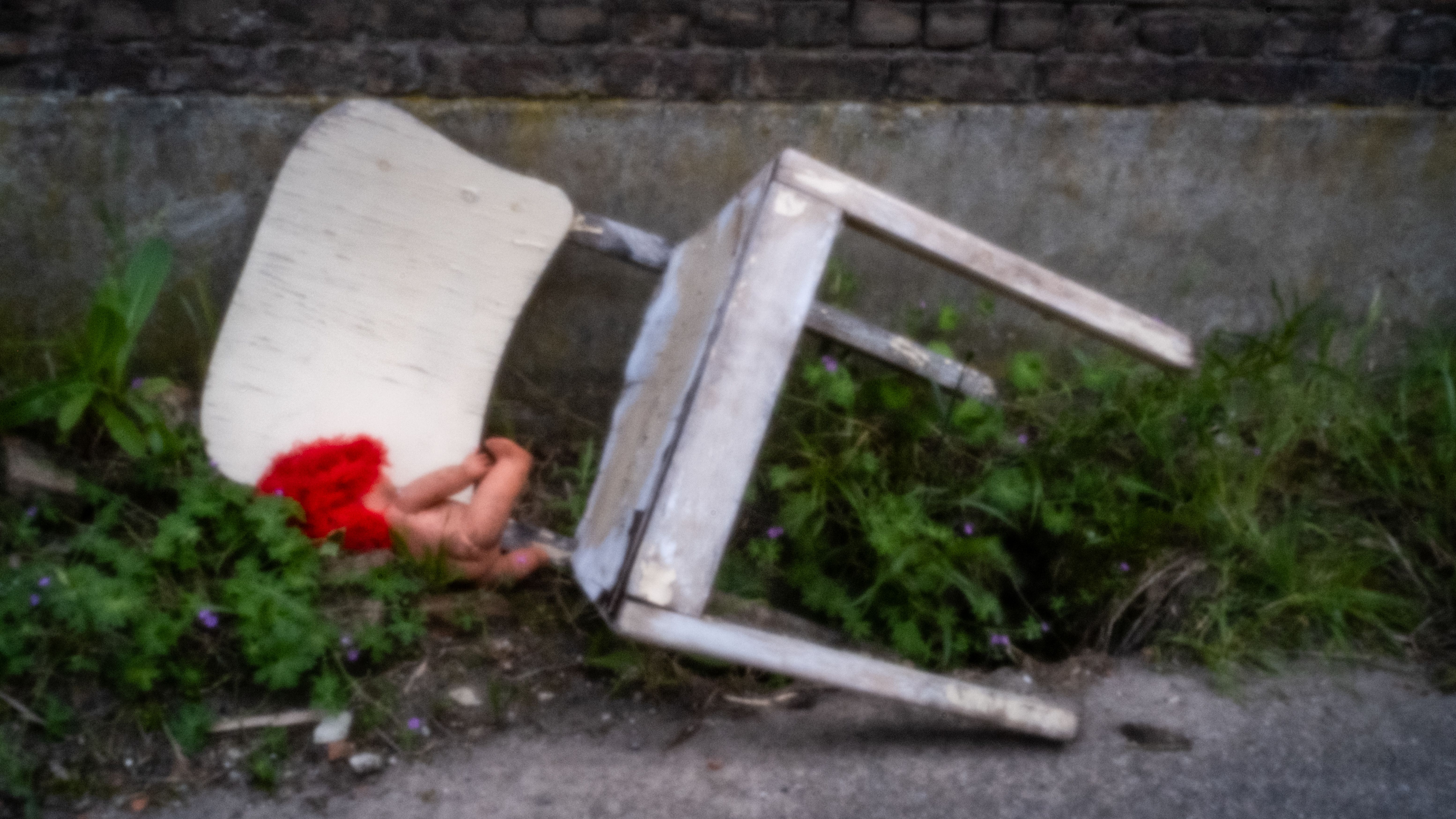 Omgevallen witte stoel met rode bloemen tussen het puin