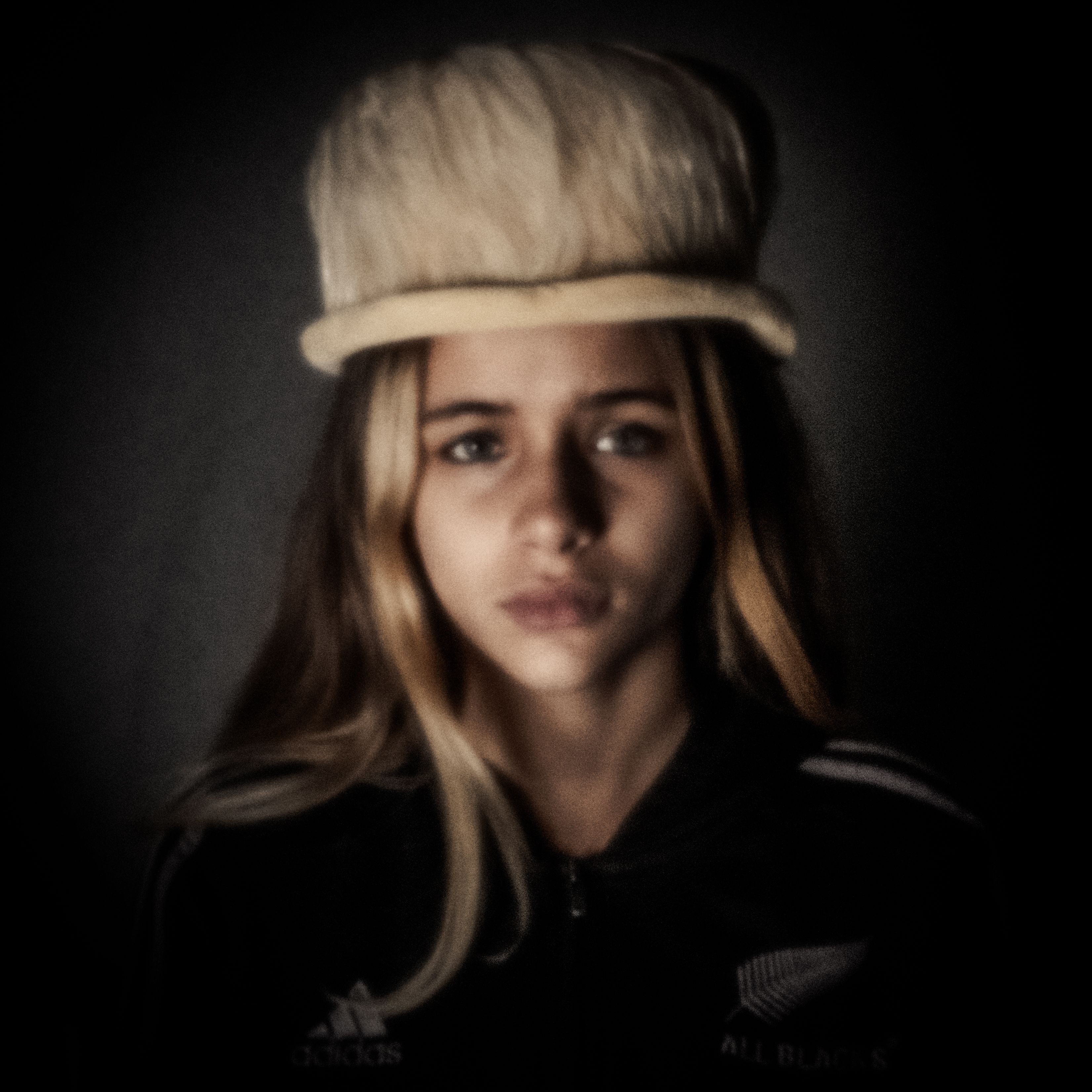 Dromerig pinhole-portret van een meisje met een grote lichte hoed, in sepia