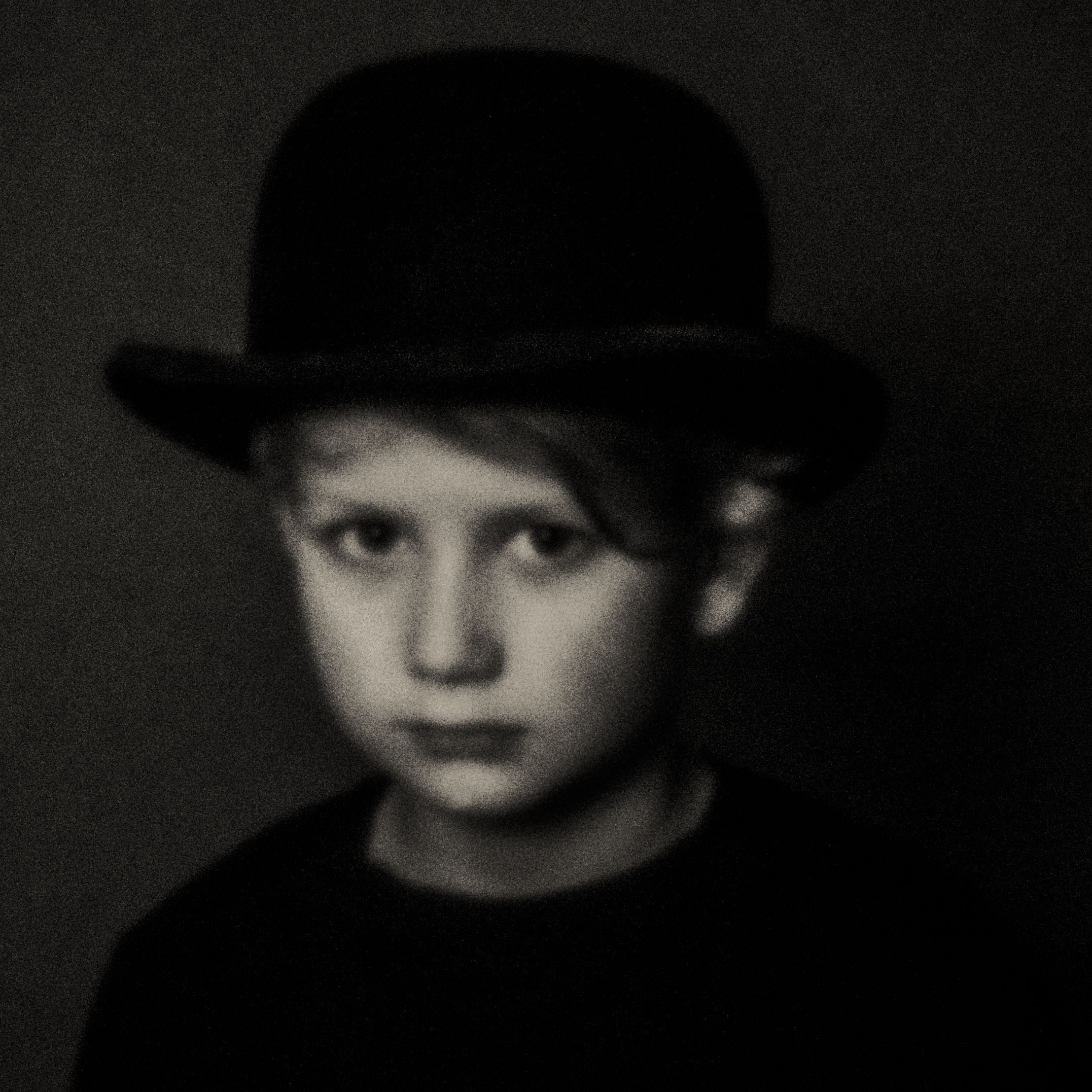 Pinhole-portret van een jongen met bolhoed, ernstige blik