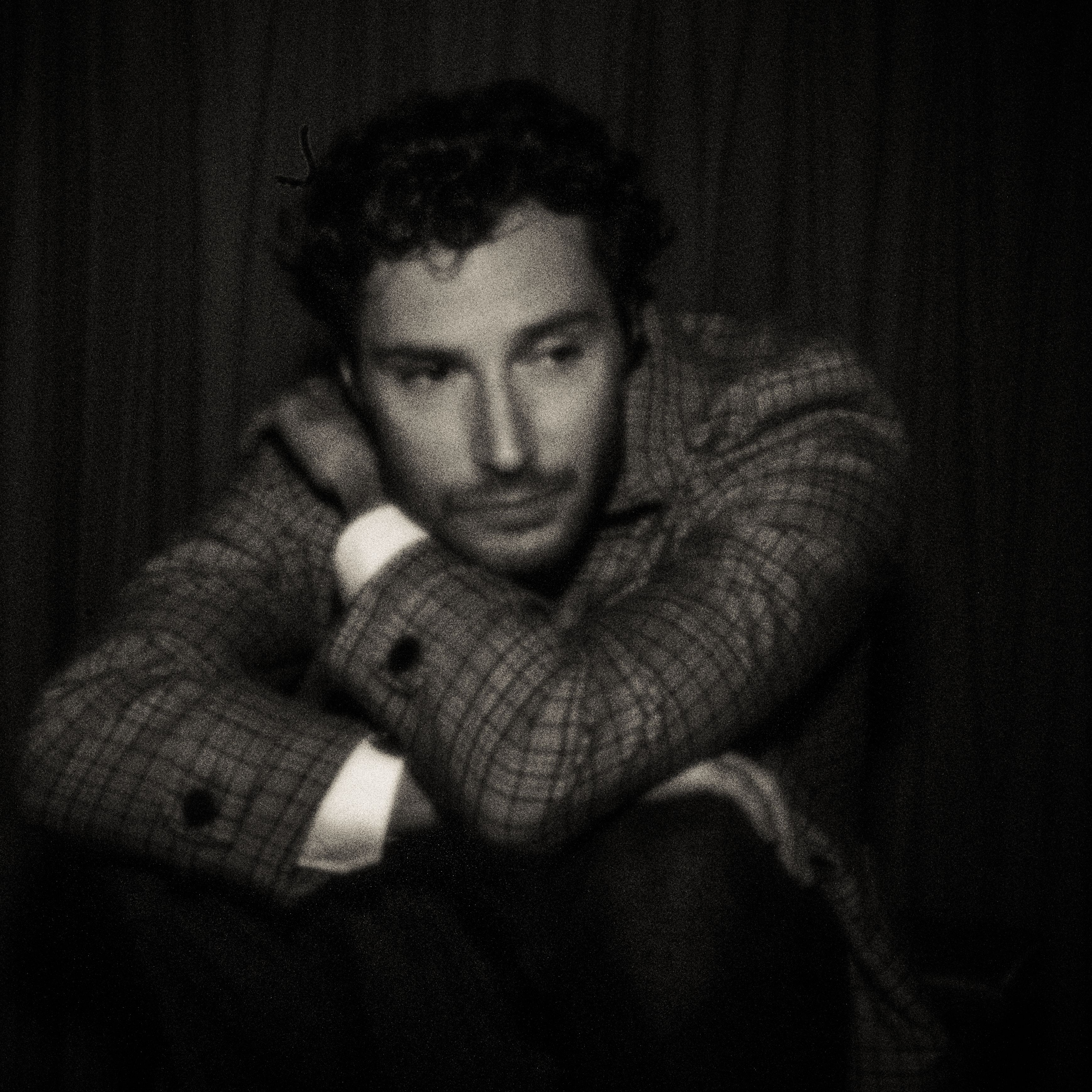 Pinhole-portret van een zittende man in geruit jasje, armen over elkaar