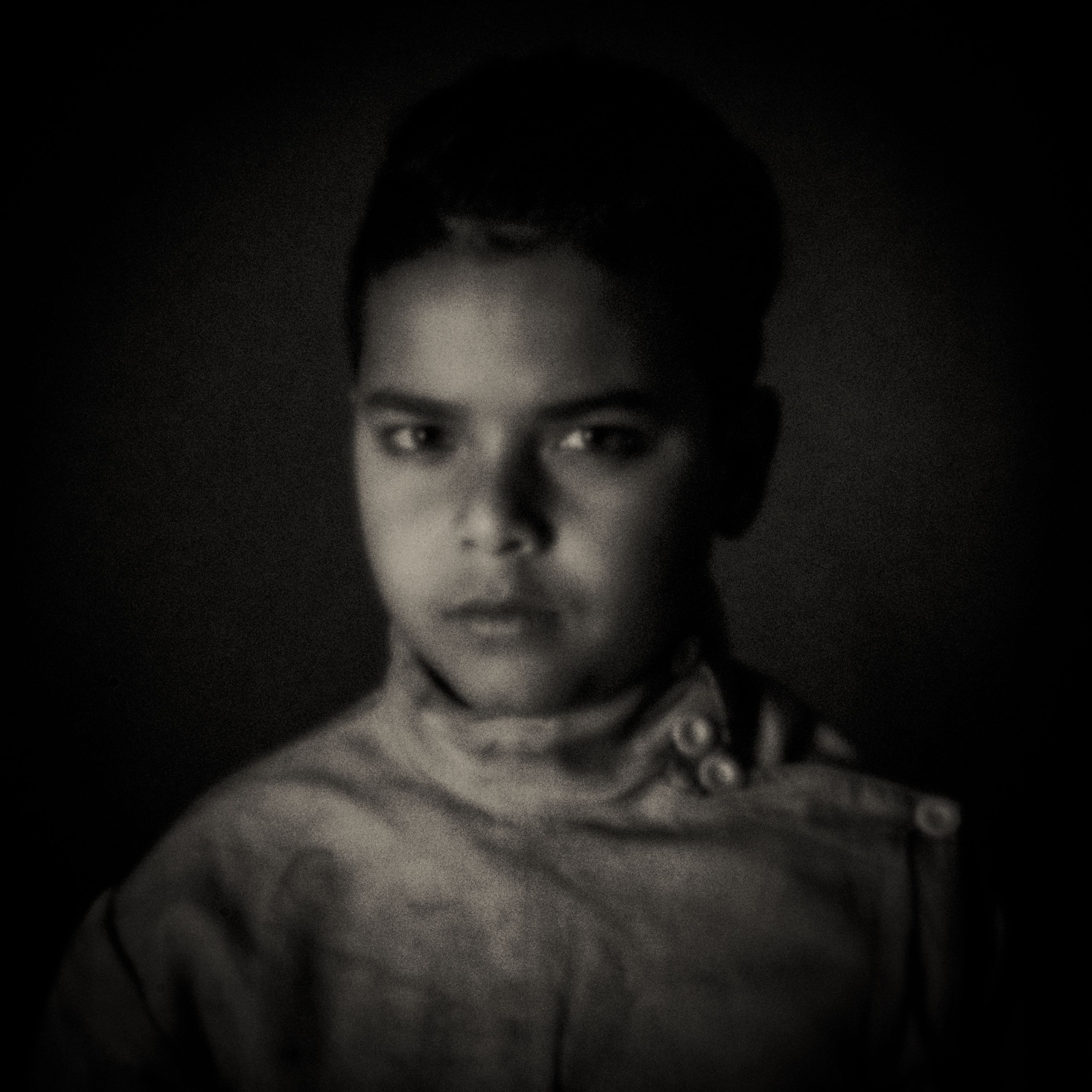 Pinhole-portret van een jongen in donkere trui, zacht licht
