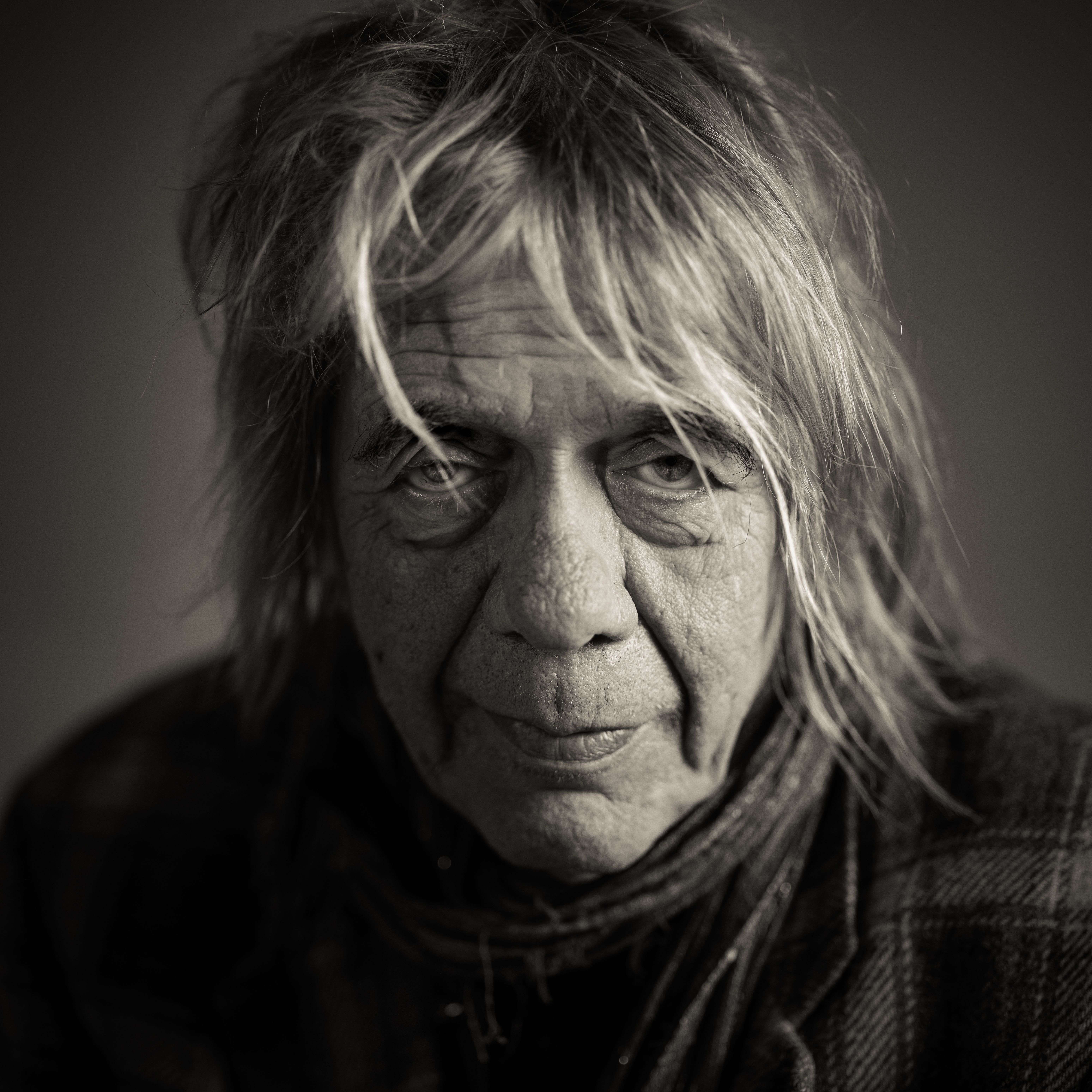 Portret van een oudere persoon met lang grijs haar, zacht licht op het gezicht