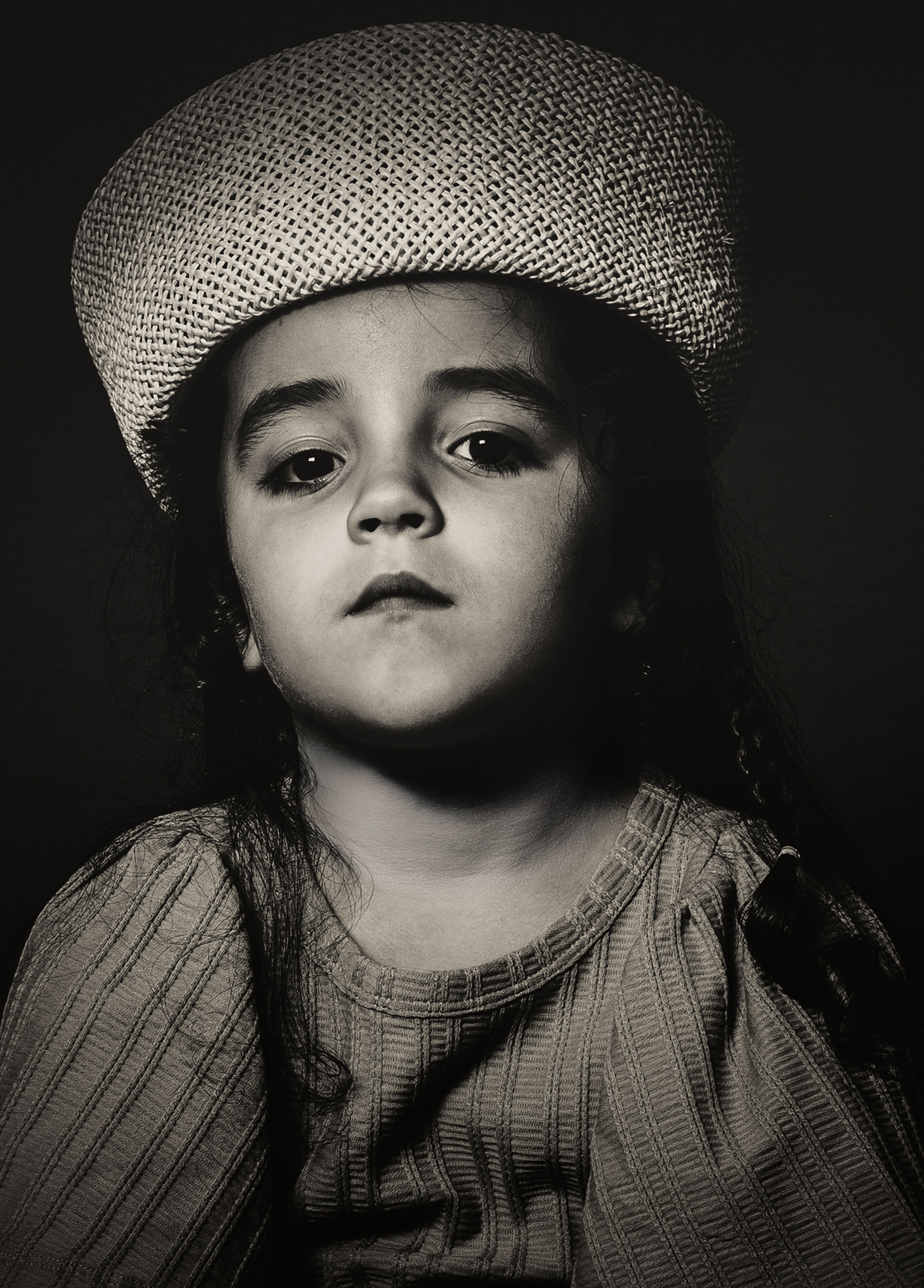 Portret van een kind met een gevlochten hoedje, warm getint tegengelicht