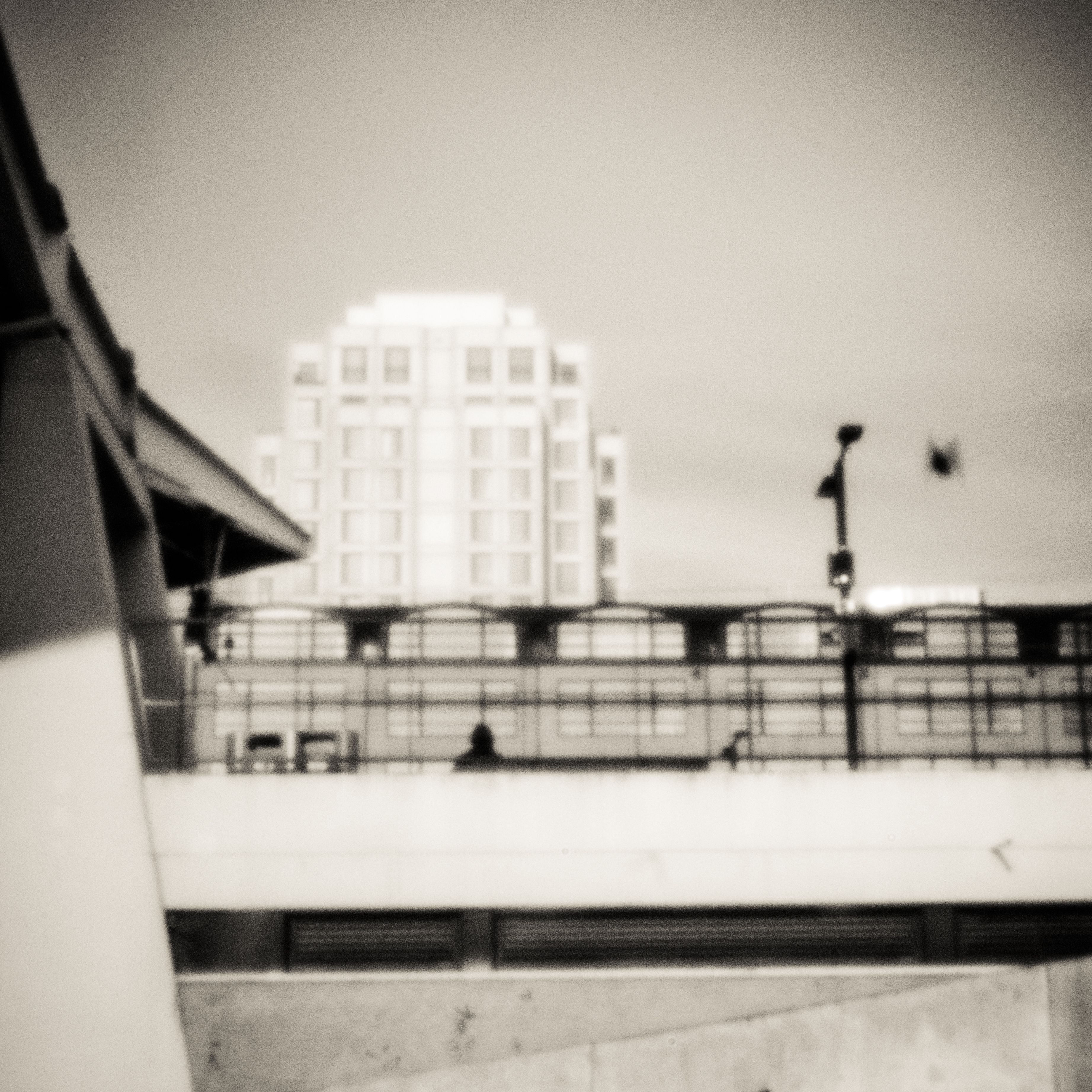 Wit gebouw boven een viaduct, gefotografeerd met pinhole-camera