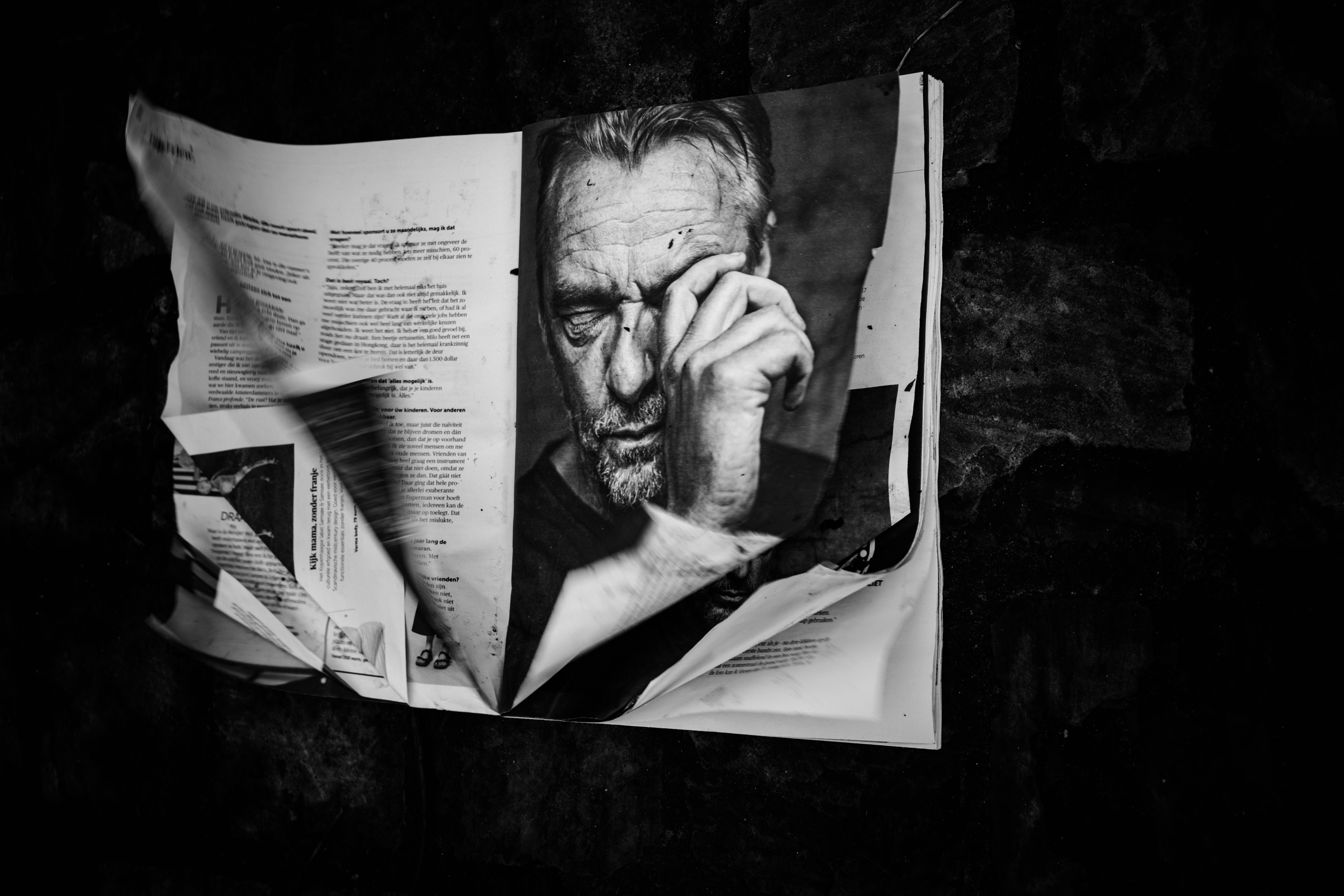 Man leest een opengeslagen tijdschrift dat zijn halve gezicht bedekt