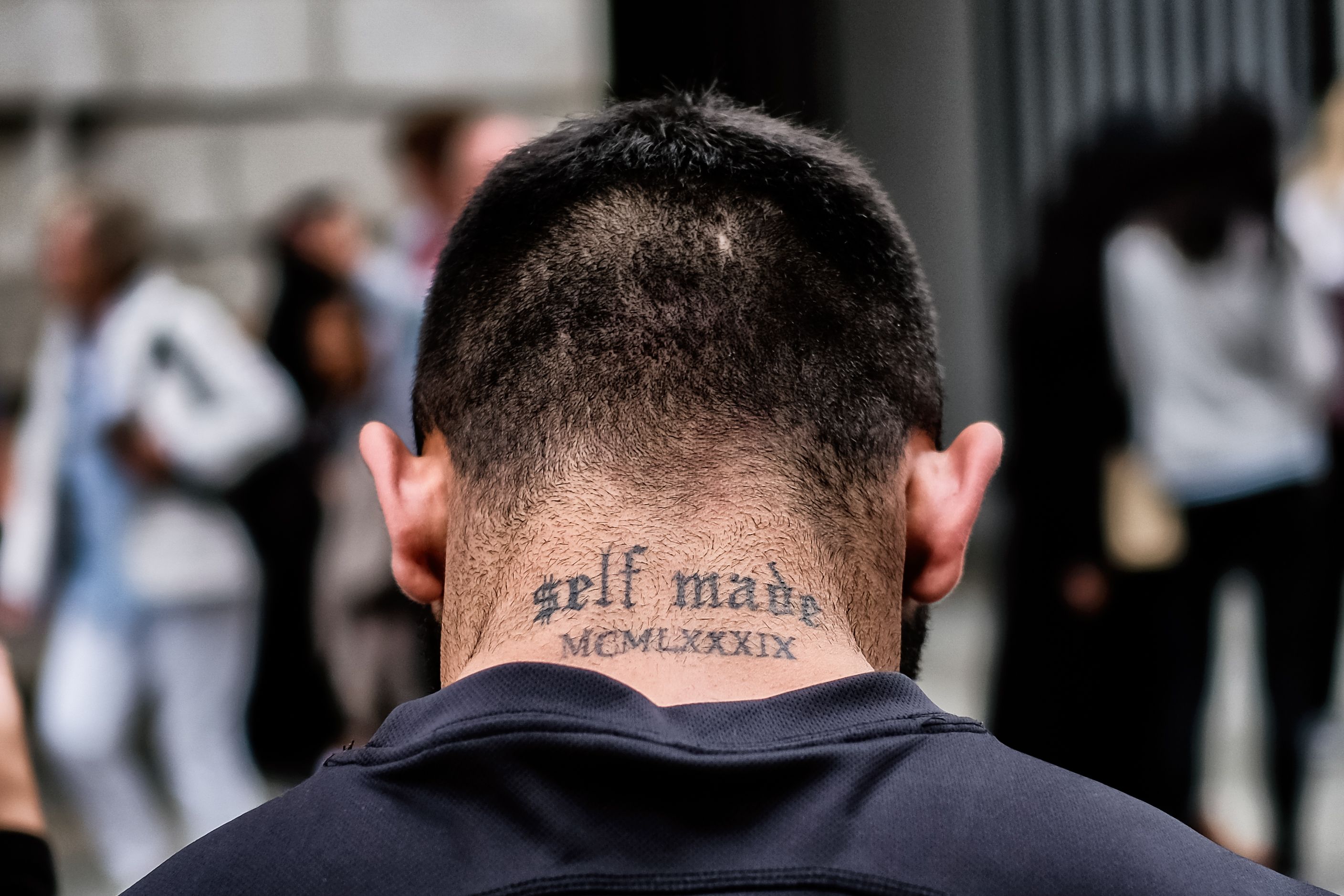 Achterhoofd van een man met de nektatoeage self made