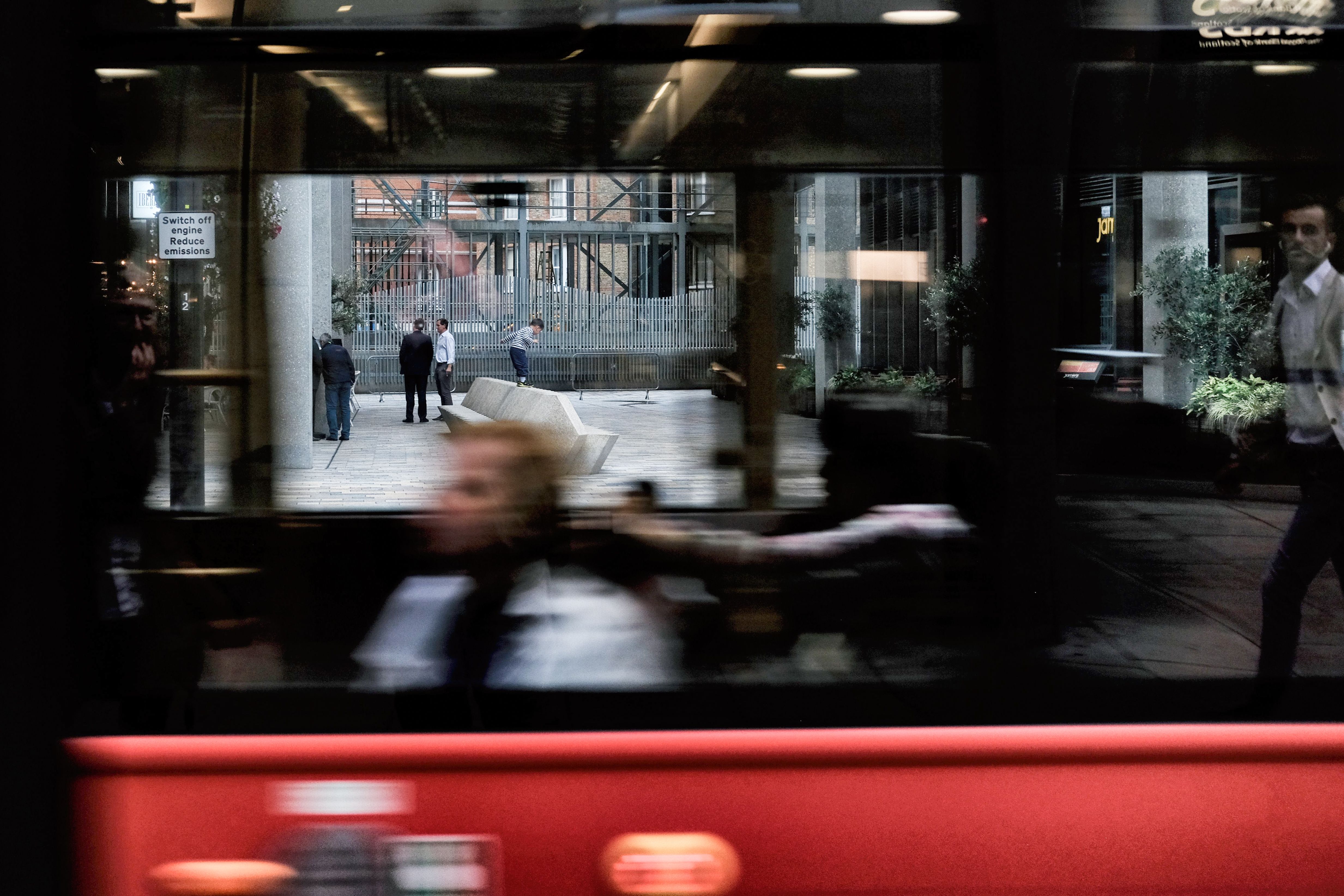 Vervaagde figuur achter het raam van een rood bankje, beweging in kleur